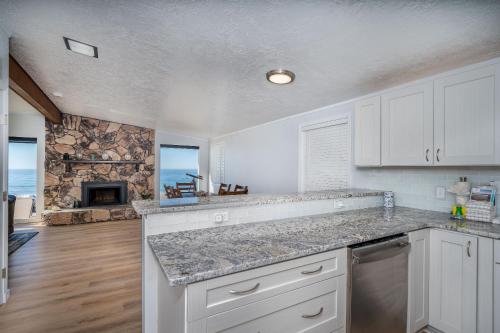 a kitchen with white cabinets and a stone fireplace at Inlet Cottage in Lincoln City