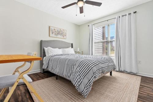a bedroom with a bed with a ceiling fan and a window at New 4BR 4BA AU Oasis 2 Mins to Downtown & Stadium Sleeps 10 in Auburn