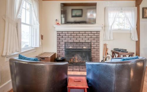 a living room with two leather chairs and a fireplace at Taft Cottage in Lincoln City