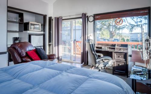 a bedroom with a bed and a desk and a balcony at Taft Cottage in Lincoln City
