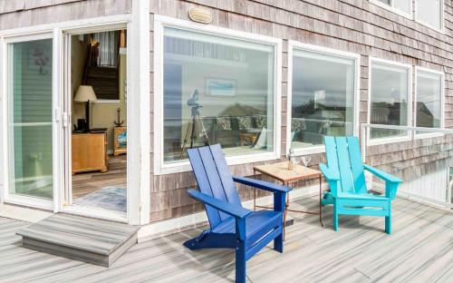 two blue chairs and a table on a porch at Seas the Day in Lincoln City