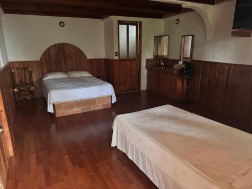 2 letti in una camera con pareti in legno e pavimenti in parquet di Posada Quetzalin a Cuetzalan del Progreso