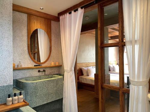 a bathroom with a tub and a bedroom with a bed at The Pink Boutique Hotel in Da Lat