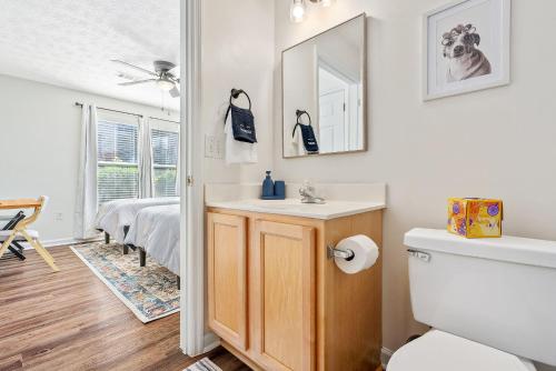 a bathroom with a sink and a toilet and a bed at New 4BR 4BA AU Oasis 2 Mins to Downtown & Stadium Sleeps 10 in Auburn