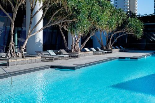 a swimming pool with palm trees and lounge chairs at Circle on Cavill - Self Contained & Privately Managed - Wow Stay in Gold Coast