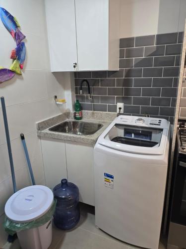 a small kitchen with a sink and a stove at Charme e requinte em Carneiros com 2 quartos in Tamandaré