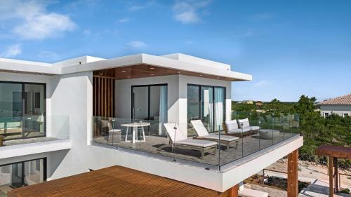 a house with a balcony with chairs and a table at Villa Julia and Villa Angelina in Leeward