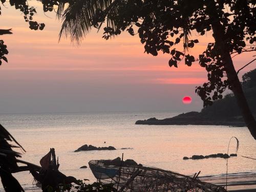 a sunset over the ocean with a boat on the beach at Eternal Forest Beach Bar&Bungalow in Koh Chang Ranong