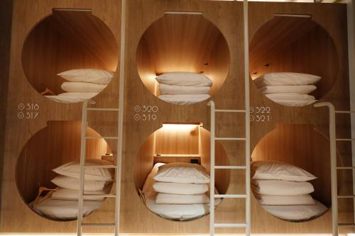 a room with three shelves with white pillows at D A L Premium Capsule Hotel in Seoul