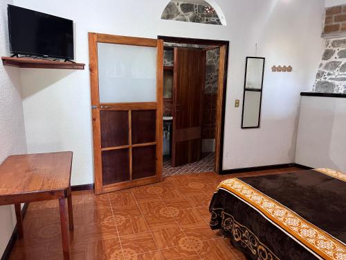 a room with a bed and a television and a table at Posada Quetzalin in Cuetzalán del Progreso