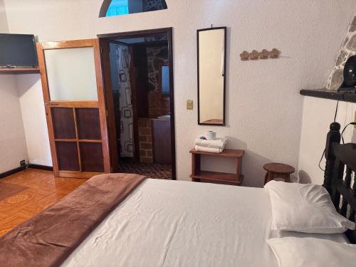 a bedroom with a white bed and a mirror at Posada Quetzalin in Cuetzalán del Progreso