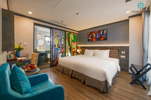 ハノイにあるSolare De Monte Hotel & Spaのベッドルーム(大型ベッド1台、青い椅子付)