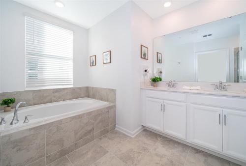 a bathroom with a tub and two sinks and a large mirror at Disney Magic ChampionsGate Resort Town Home 15 min from Disney World, 7 Pools, Gym, Golf, Arcade, Water Park and more! in Kissimmee