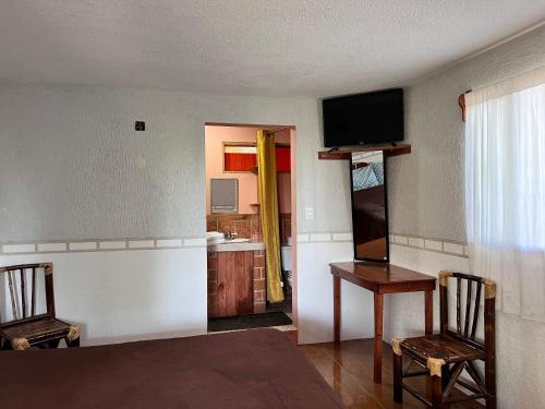 a room with a table and two chairs and a television at Posada Quetzalin in Cuetzalán del Progreso