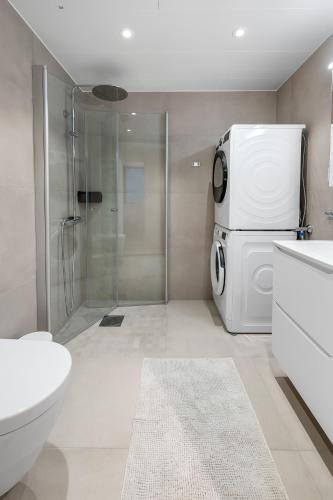 a bathroom with a shower and a refrigerator at Northern Lights Haven 2BD Apartment sea view in Tromsø