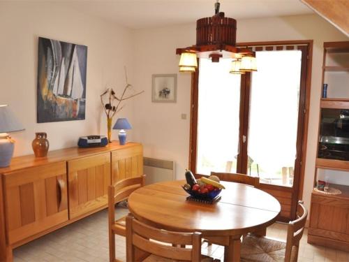une salle à manger avec une table et des chaises en bois dans l'établissement Maison cosy à 250m de la plage de Pors Gelen avec jardin et parking - FR-1-368-446, à Pleumeur-Bodou
