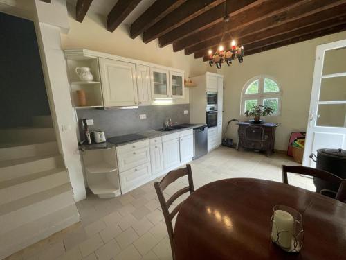 une cuisine avec des armoires blanches et une table en bois dans l'établissement Gîte de charme aux portes d'Amboise avec grand jardin et Wi-Fi - FR-1-381-604, à Reugny