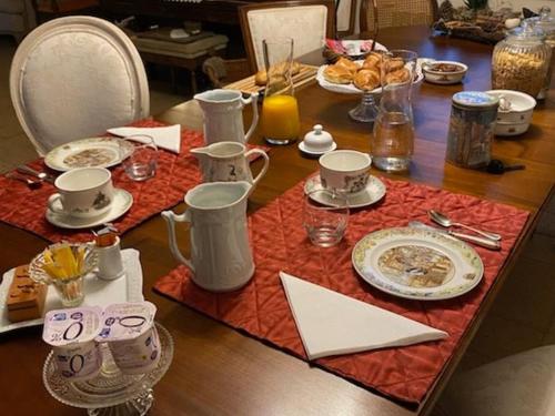 a table with a table set with plates and cups at Chambre spacieuse avec piscine et parking privé - FR-1-410-464 in Montreuil-le-Henri