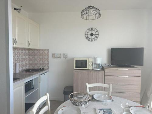 une petite cuisine avec une table et un micro-ondes dans l'établissement Studio face à la mer pour 4, parking, balcon - Notre-Dame-de-Monts - FR-1-540-310, à Notre-Dame-de-Monts