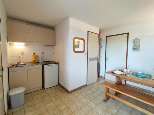 une cuisine avec des armoires blanches et une table en bois dans l'établissement T2 avec piscine, tennis & parking - Proche plage - 3/4 pers - FR-1-795-54, à Fleury