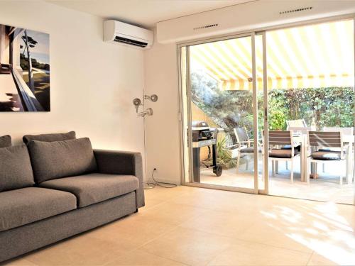 un salon avec un canapé et une porte coulissante en verre dans l'établissement Appartement 2P Climatisé avec Jardin et Parking près de la Mer - FR-1-226B-223, à Cavalaire-sur-Mer