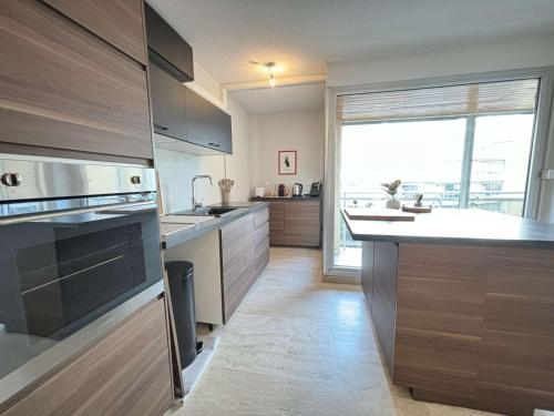 une cuisine avec des placards en bois et une grande fenêtre dans l'établissement Studio moderne avec terrasse sur le toit, parking et WIFI - FR-1-226B-225, à Cavalaire-sur-Mer