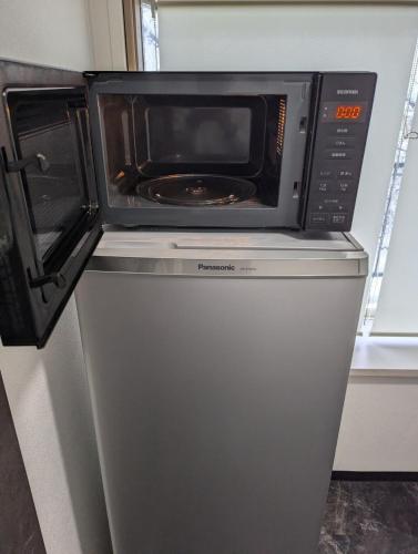a microwave oven sitting on top of a refrigerator at DoggoInnn Akita 最大8人で泊れる ペットと泊まれる宿 繁華街まで徒歩3分の好立地 in Akita