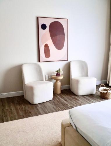 two white chairs and a bed in a bedroom at Sheema Lodge in Hatta
