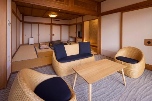 a room with couches and a table and chairs at Biwako Ryokusuitei in Otsu
