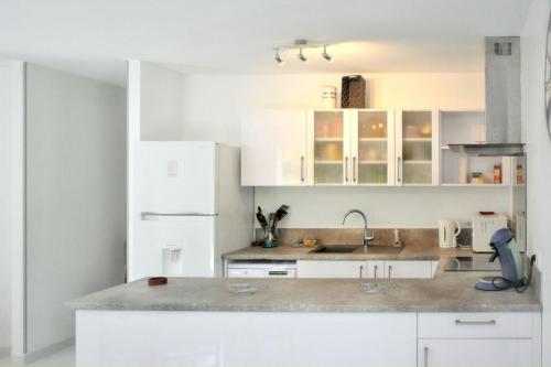 une cuisine blanche avec des armoires blanches et un évier dans l'établissement Charmante maison avec jardin à Arcachon, parfaite pour 6 personnes, à Arcachon