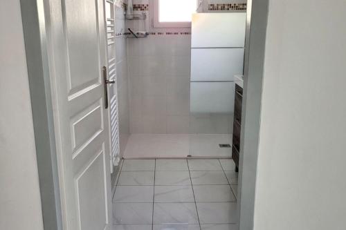 La salle de bains blanche est pourvue d'une douche et d'une porte. dans l'établissement Charmante maison avec jardin à Arcachon, parfaite pour 6 personnes, à Arcachon