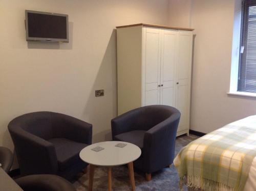 a bedroom with two chairs and a table and a bed at Rooms @ Number Six in Oakham