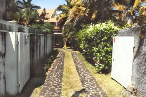 a path with a white fence and palm trees at Charming Bungalow in Blue Bay with Terrace in Blue Bay
