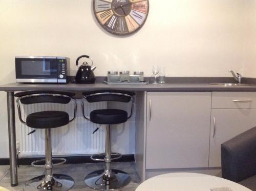 a kitchen with a counter with two bar stools and a microwave at Rooms @ Number Six in Oakham
