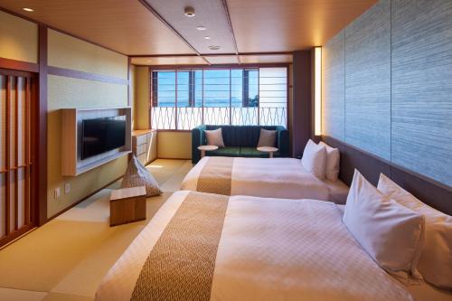 a hotel room with two beds and a flat screen tv at Biwako Ryokusuitei in Otsu