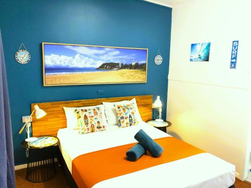 a bedroom with a bed with an orange and blue wall at Acacia Motel in Chinchilla