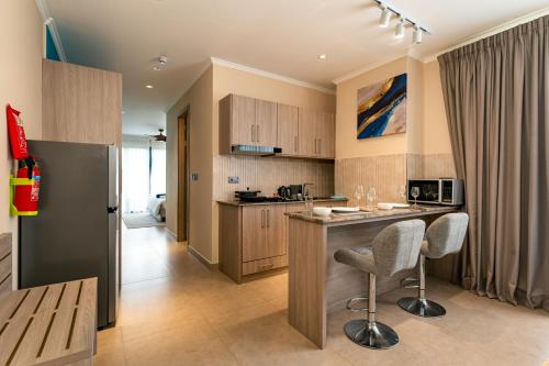 a kitchen with a refrigerator and two bar stools at Thalassa Seychelles in Beau Vallon