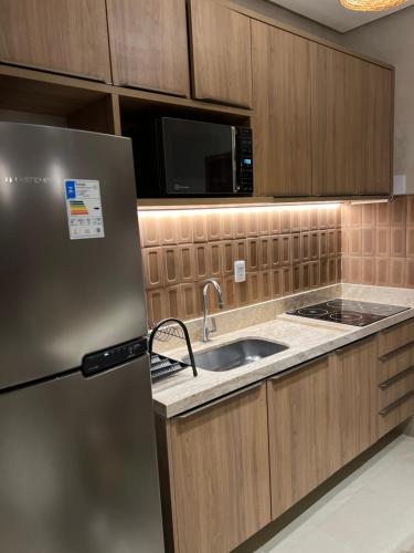 a kitchen with a refrigerator and a sink at Chalé Encantador com Rooftop Privativo in Cajueiro