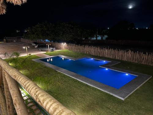 a blue swimming pool in a yard at night at Chalé Encantador com Rooftop Privativo in Cajueiro