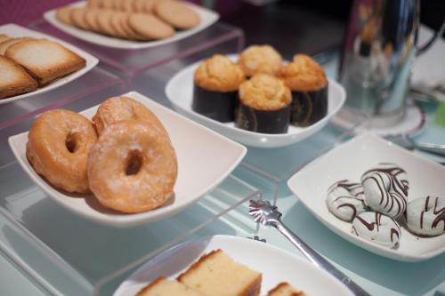 a glass table with plates of donuts and pastries at Silken Rona Dalba in Salamanca