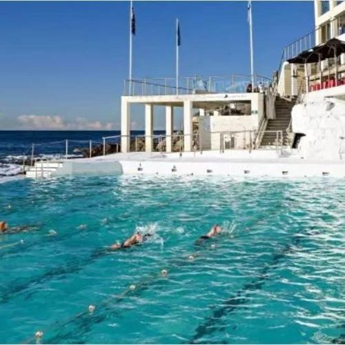 a group of people swimming in the water near a boat at Bondi 38 Serviced Apartments in Sydney