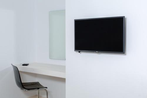 a tv on a white wall next to a chair at Princess Of Naxos in Naxos Chora