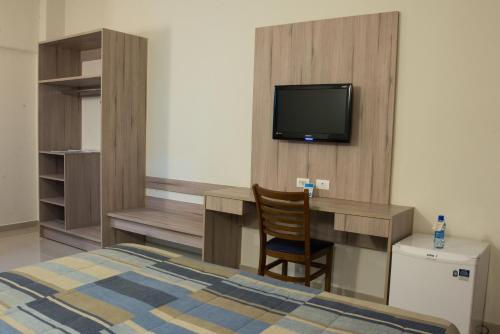a bedroom with a bed and a desk and a tv at Hotel Estação 101 - Itajaí in Itajaí