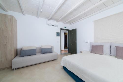 a white bedroom with a bed and a couch at Princess Of Naxos in Naxos Chora