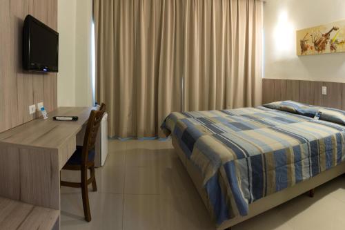 a bedroom with a bed and a desk and a television at Hotel Estação 101 - Itajaí in Itajaí