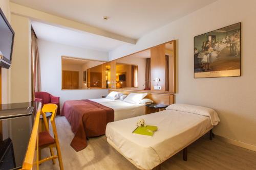 a hotel room with two beds and a tv at Silken Rona Dalba in Salamanca