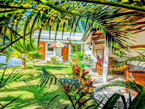 a garden with plants and a house with an umbrella at Astillo's Guest Houses in Moalboal