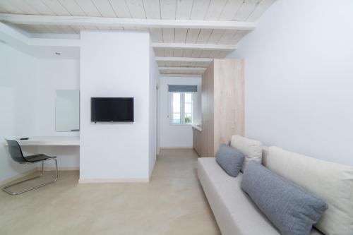 a white living room with a couch and a tv at Princess Of Naxos in Naxos Chora