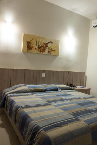 a bedroom with a bed and a painting on the wall at Hotel Estação 101 - Itajaí in Itajaí