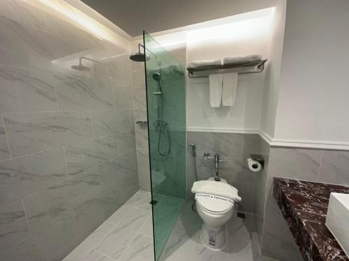 a bathroom with a toilet and a glass shower at Elizabeth Hotel in Bangkok